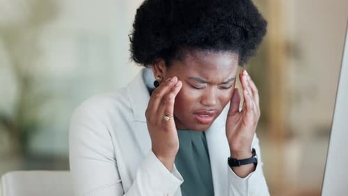 Stressed female suffering from headache and burnout while trying to reach deadline at office