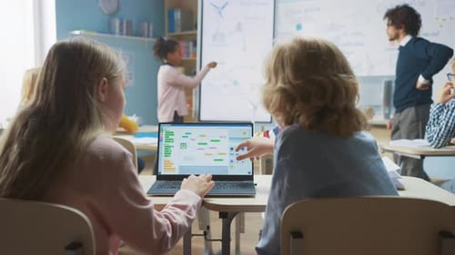 Clase de ciencias de la escuela primaria: niños y niñas por encima del hombro usan una computadora portátil con pantalla Showi