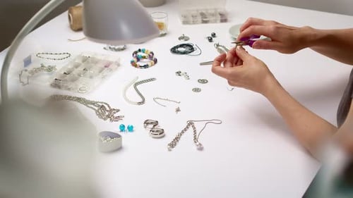 Woman Assembling Silver Spiral Earrings at Table