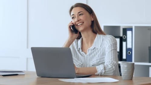 Smiling Woman Talking on Phone at Desk