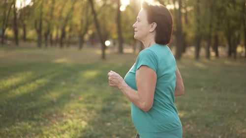 Senior Woman Jogging in Park at Sunset