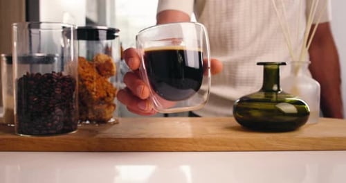 Man holding a cup of black coffee indoors
