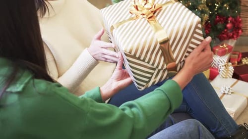 Two Young Women Exchange a Beautifully Wrapped Gift at Christmas