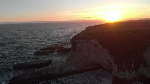 A sunset footage of cliffs and waves crashing at the pacific coast.
