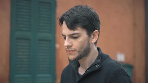 Pensive Young Adult Looks At Camera Outdoors