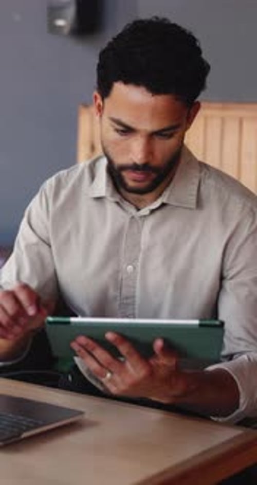 Tablet, remote work and man in cafe, reading report or creative review with laptop for newsletter