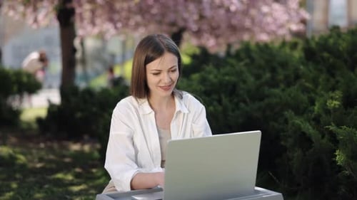 Woman Working on Laptop in Springtime Park