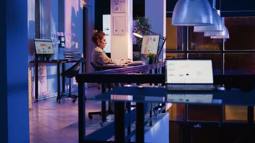 Woman Working Late at Computer in Bright Office