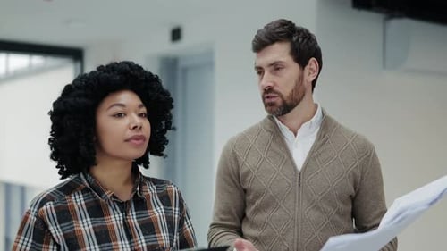 Business Colleagues Collaborate on Blueprints in a Modern Office