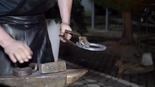 Blacksmith Shaping Metal on Anvil at Night