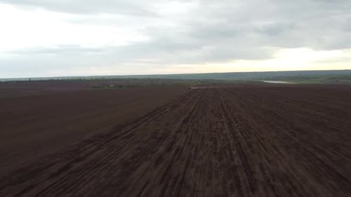 Blue tractor with yellow seeder working on the field in Ukraine OA