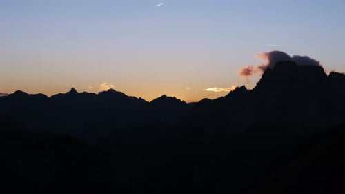 Mountain silhouette of italian alps at sunrise glowing sky