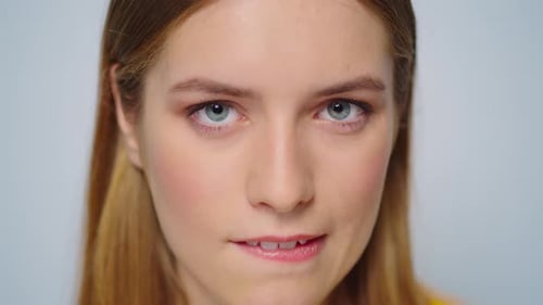 Sensual blonde european woman bites lip and flirts with camera in slow motion studio