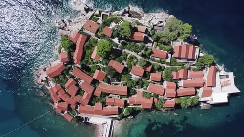A drone flies over the island of Sveti Stefan on a sunny day in Montenegro