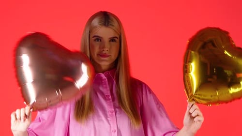 Smiling Woman Holding Heart Balloons on Red Background