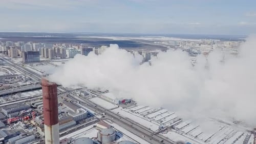 Huge factory pipe with lot's of smoke aerial view on industrial city, flying through fog