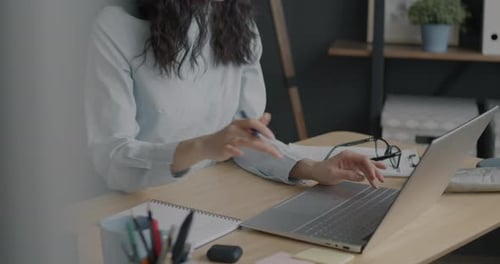 Portrait of Ambitious Asian Business Lady Typing with Laptop and Writing Info in Notebook in Office