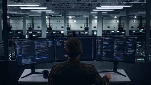 Back View Of Asian Military Using Computer To Write Code In Data Center