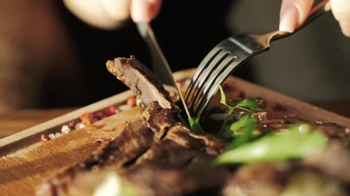 Woman cutting a steak on a wooden board