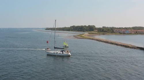 Drone cinématique/prise de vue aérienne d'un bateau naviguant sur l'océan avec un port de plaisance en arrière-plan avec une