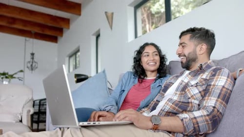 Smiling Couple Relaxing on Couch with Laptop