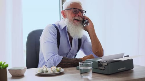 Senior Man Talking on Phone at Desk Indoors