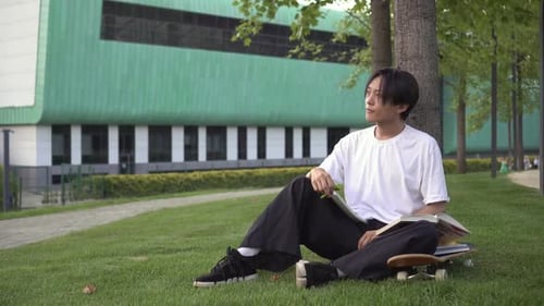 Young Adult Studying Outdoors on Campus Lawn