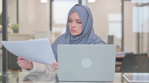 Arabische Frau arbeitet an Dokumenten und Laptop