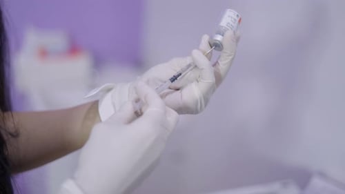 Hands of Doctor Extracting Solution From Vial Using Needle and Syringe in Slow Motion