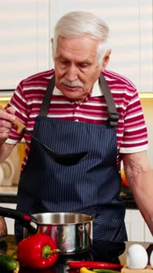 Senior Man Cooking Soup in Bright Home Kitchen