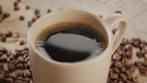 Close Up of Coffee Mug Surrounded by Beans