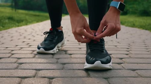 Woman Runner Tying Shoelaces in Park