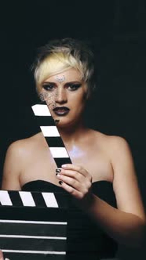 Woman with movie clapboard. Young woman with movie clapboard isolated on black background