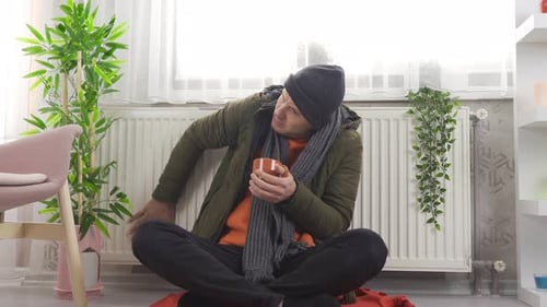 Cold Man Warming Himself with Mug Indoors