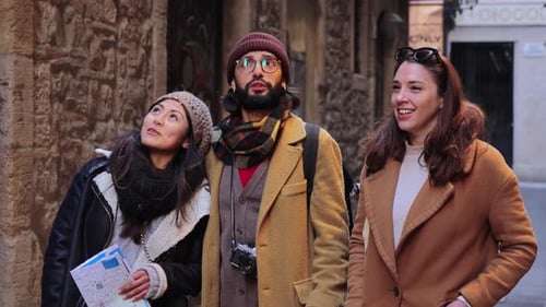 A Group of Happy Tourist Friends Walking and Pointing the Direction Sightseeing on a City Three