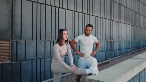 Personal Trainer Guiding Woman in Leg Stretching Exercise Outdoors