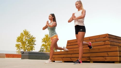 Two young women exercising outdoors on sunny day