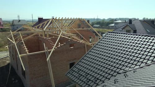 Aerial View of Unfinished Residential House with Wooden Roof Frame Structure Under Construction