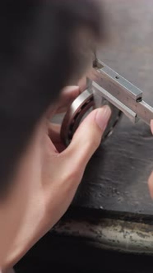 Overhead View of Lab Technician Measuring Metal Object with Vernier Caliper