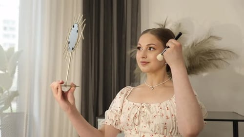 Woman Applies Makeup Looking in Mirror at Home