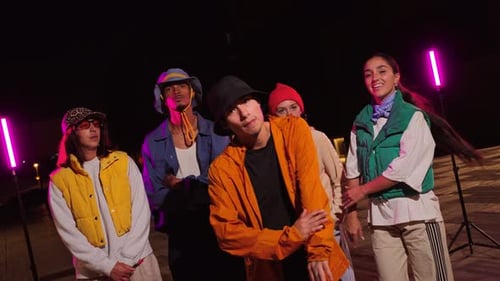 Grupo energético de amigos realizando movimentos dinâmicos de dança juntos em um ambiente urbano envolvente