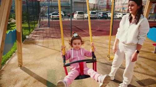 Ein freudiges Schaukelabenteuer Ein fürsorglicher Erwachsener hilft einem kleinen Kind, den Nervenkitzel des Spielens auf einem
