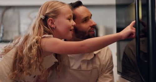 Girl and Man Looking in Oven in Kitchen