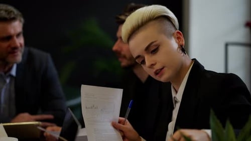 Fünf Kollegen bereiten Dokumente vor, bevor sie wichtige Verhandlungen mit Geschäftsleuten aus dem Büro führen