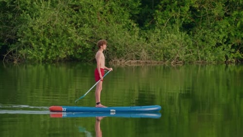 Alone Boy Floating on Stand Up Paddle Board in Lake in Summertime Standup Paddleboarding Surfer Rows