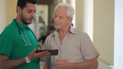 Doctor Showing Senior Patient Information on Tablet