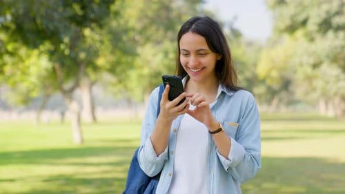Woman Smiles Using Smartphone in Green Park