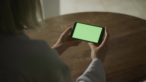 Person Viewing Smartphone with Green Screen
