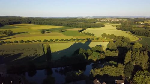 Aerial dolly out of German Abbey and its towers surrounded by green fields and dense forest in count