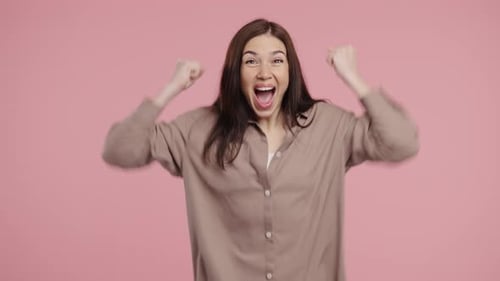 Happy Woman Makes Victory Yes Clenched Fist Joy Triumphant Expression on Pink